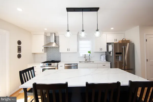 a kitchen with kitchen island a stove a refrigerator a sink a dining table and chairs