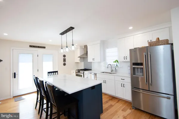 a kitchen with stainless steel appliances a refrigerator a sink a stove a dining table and chairs