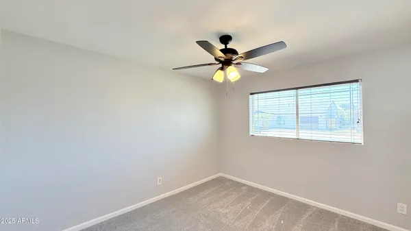 an empty room with a window and a fan