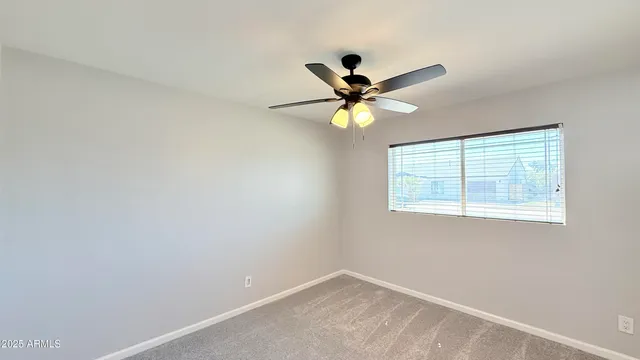 an empty room with a window and a fan