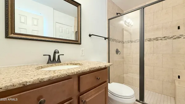 a bathroom with a granite countertop sink toilet and shower