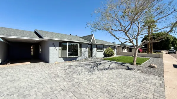 a view of a house with a yard and large tree