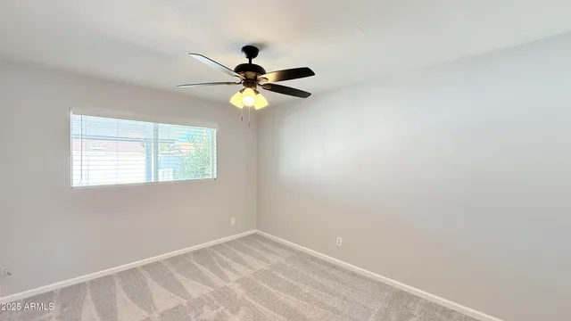 an empty room with a window and a fan
