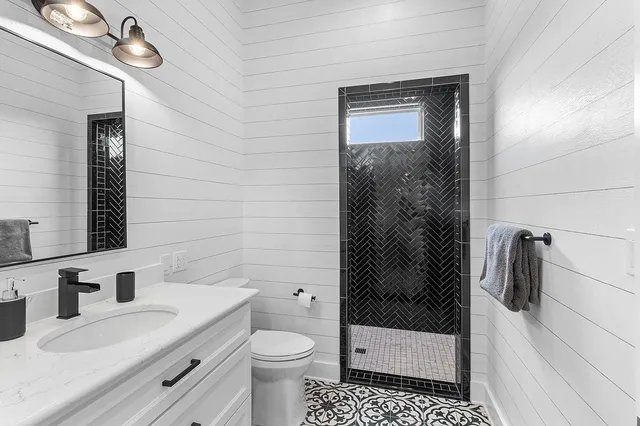 a bathroom with a granite countertop sink a toilet and shower