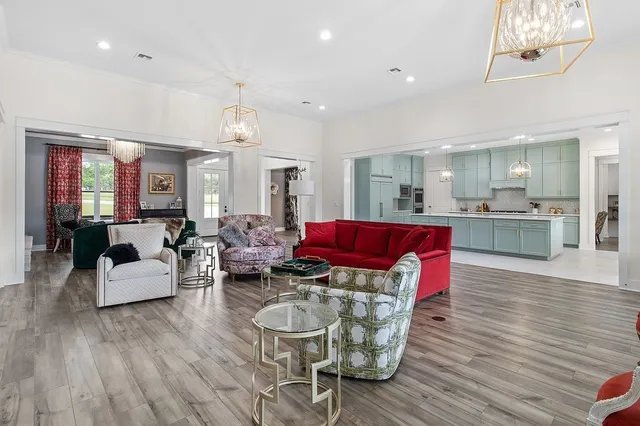 a living room with furniture wooden floor and a kitchen view