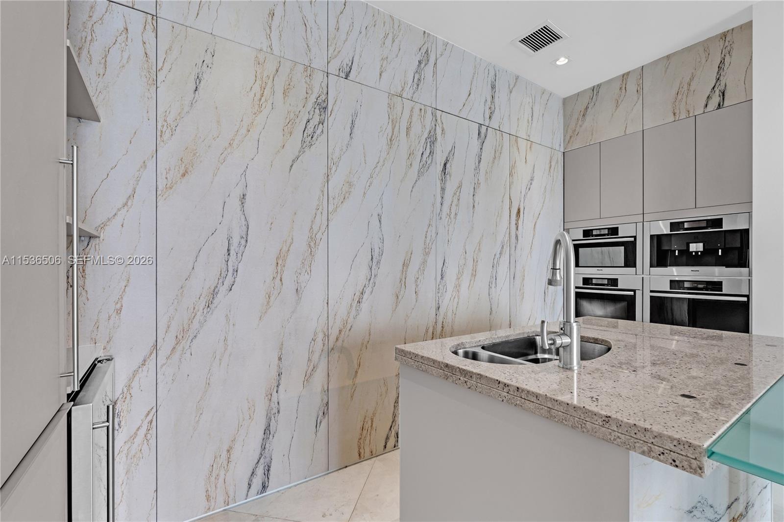 900 Brickell Key Boulevard, Unit 1002 Miami, FL 33131 - Photo 62 of 87 a kitchen with stainless steel appliances granite countertop a sink a stove and a refrigerator