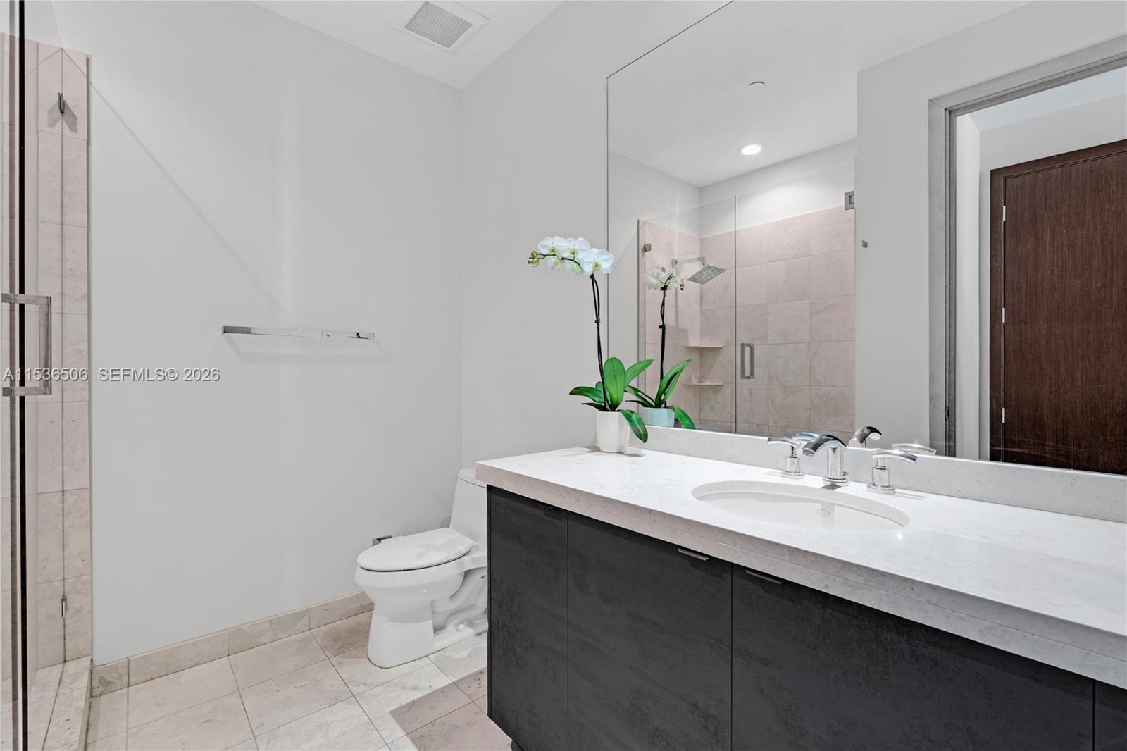 900 Brickell Key Boulevard, Unit 1002 Miami, FL 33131 - Photo 66 of 87 a bathroom with a granite countertop sink a toilet and a mirror