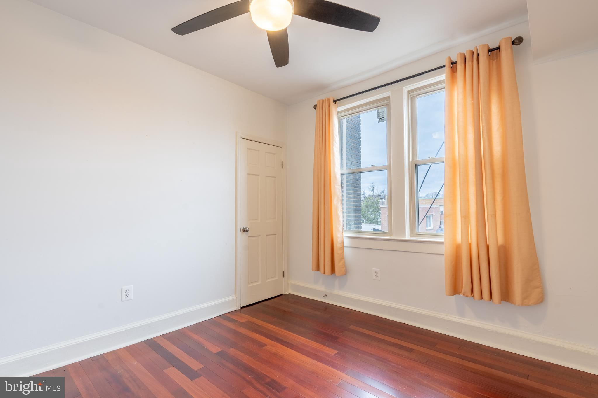1725 Lanier Place Northwest, Unit 9C Washington, DC 20009 - Photo 15 of 18 an empty room with wooden floor fan and windows