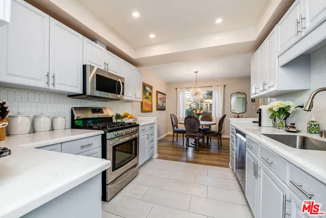 a kitchen with stainless steel appliances granite countertop a refrigerator a sink dishwasher a microwave oven with white cabinets and wooden floor