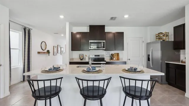 a kitchen with stainless steel appliances a dining table chairs microwave and sink