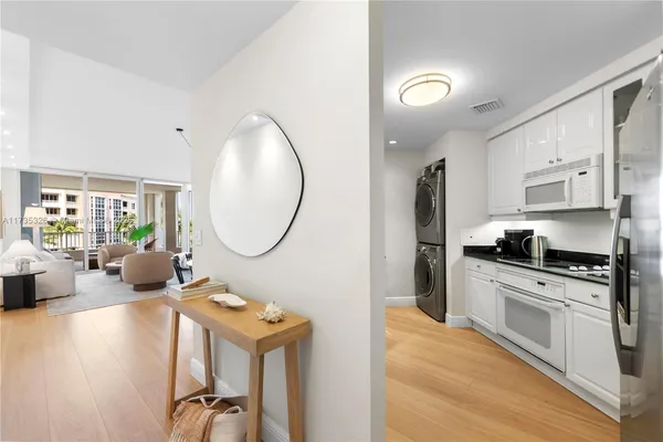 a very nice looking kitchen with granite countertop a stove a sink a refrigerator and white cabinets with wooden floor