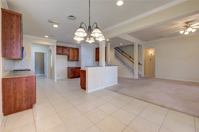 a view of an empty room with chandelier fan and fire place