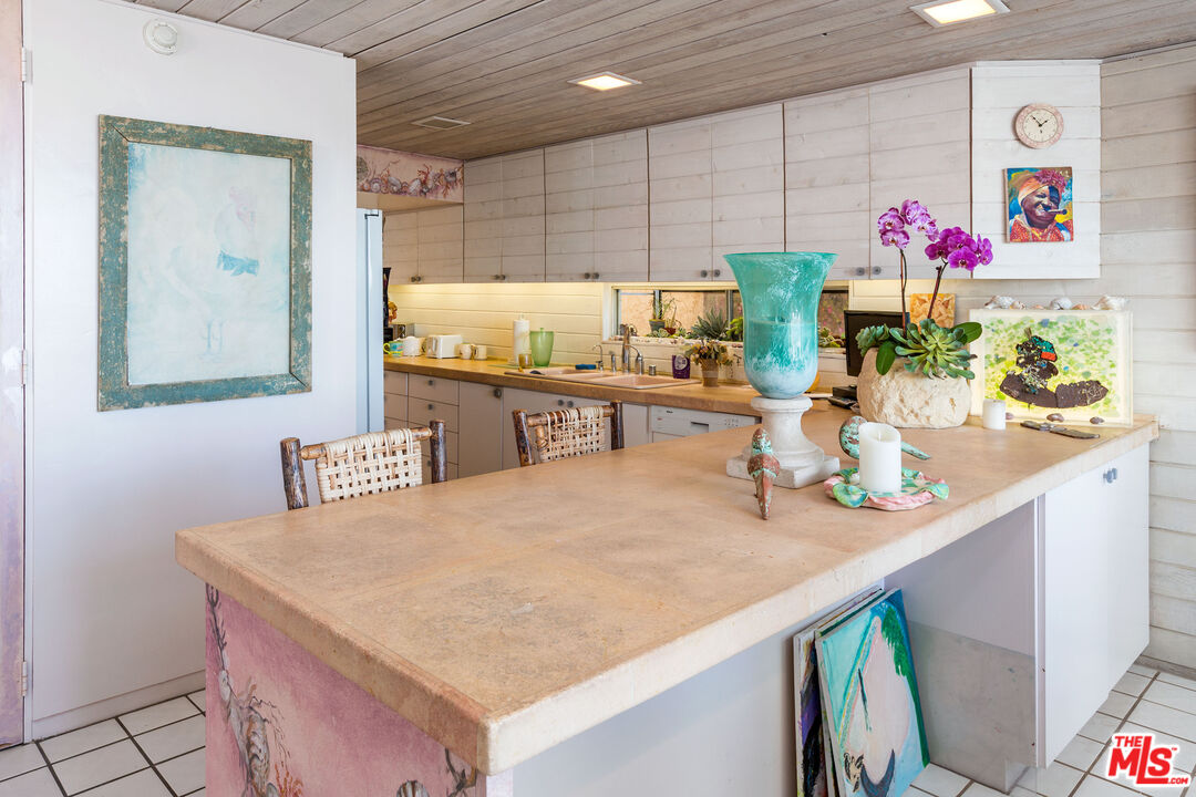 24102 Malibu Road Malibu, CA 90265 - Photo 8 of 14 a room with stainless steel appliances kitchen island granite countertop a table chairs and a wooden floor
