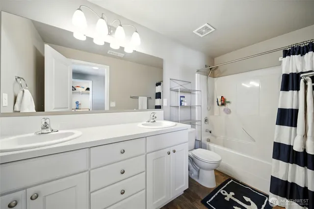 a spacious bathroom with a double vanity sink toilet mirror and shower