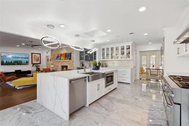 a large white kitchen with stainless steel appliances granite countertop a stove and a sink
