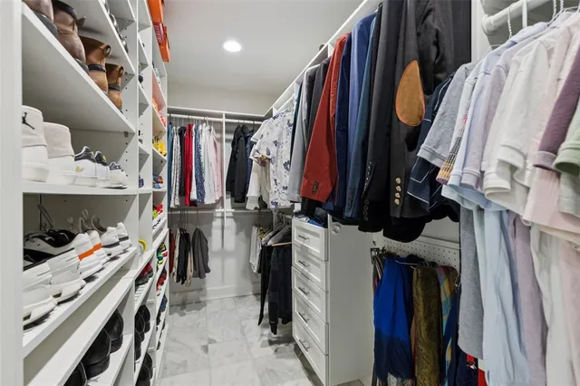 a view of walk in closet with clothes and shoes