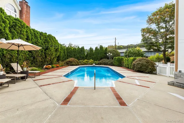 a view of a swimming pool with lawn chairs under an umbrella