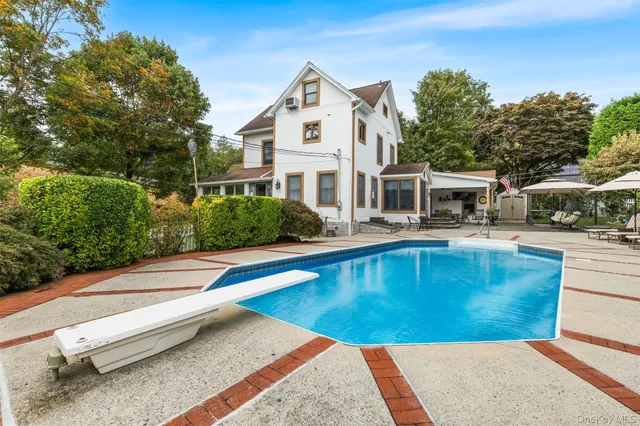 a view of a house with pool lawn chairs and a barbeque