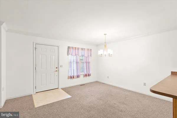 an empty room with chandelier fan and windows