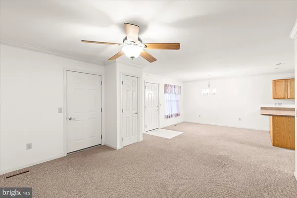 an empty room with chandelier fan and windows