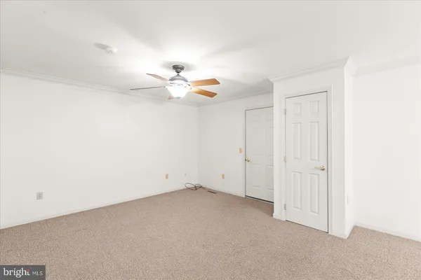 an empty room with a chandelier fan and windows