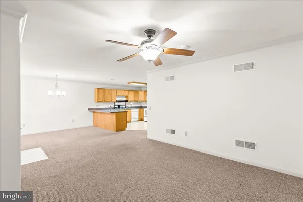 an empty room with chandelier fan and windows