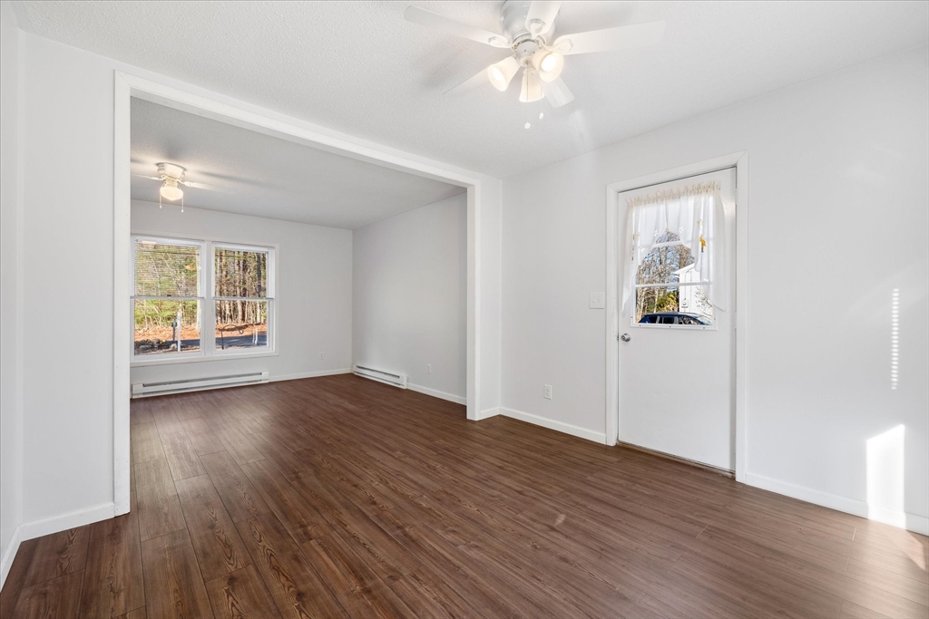 359 Bemis Road Warren, MA 01585 - Photo 12 of 27 an empty room with wooden floor chandelier fan and windows