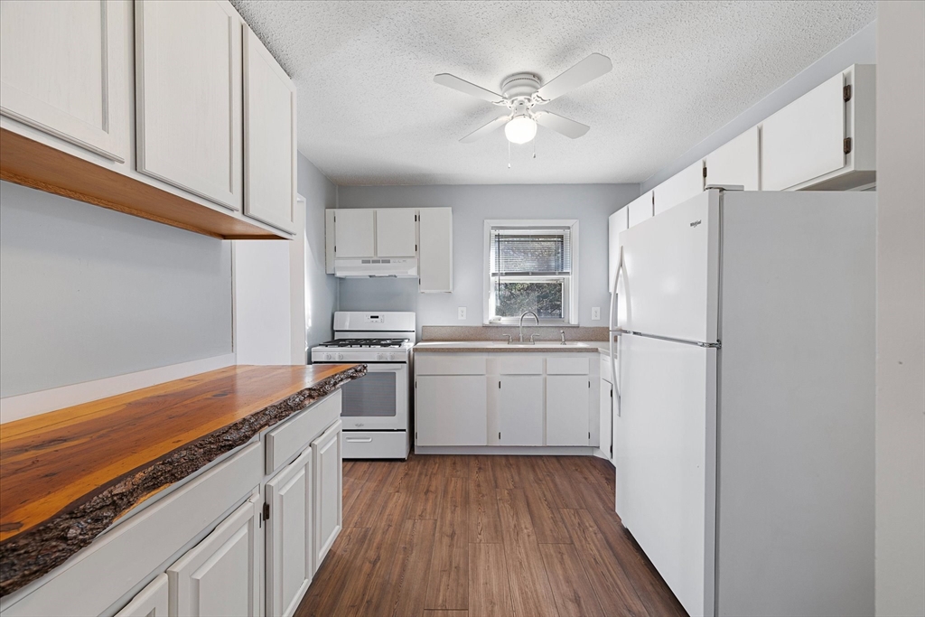 359 Bemis Road Warren, MA 01585 - Photo 13 of 27 a kitchen with a refrigerator a sink and dishwasher a stove top oven with wooden floor