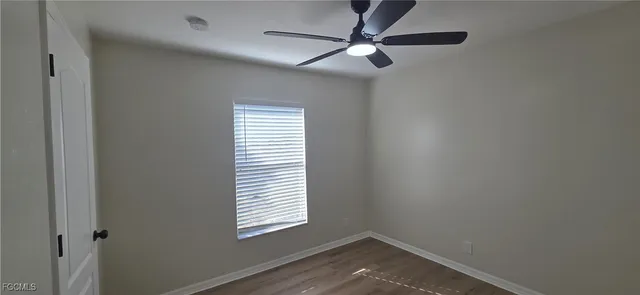 a view of empty room with window and wooden floor