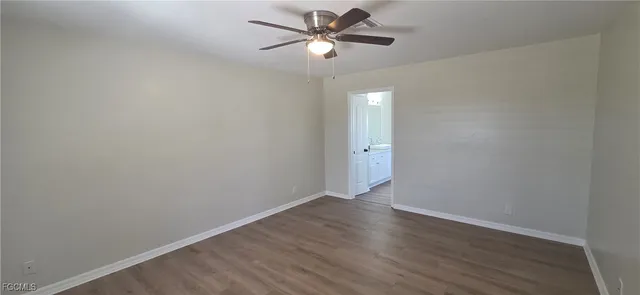 an empty room with wooden floor fan and windows