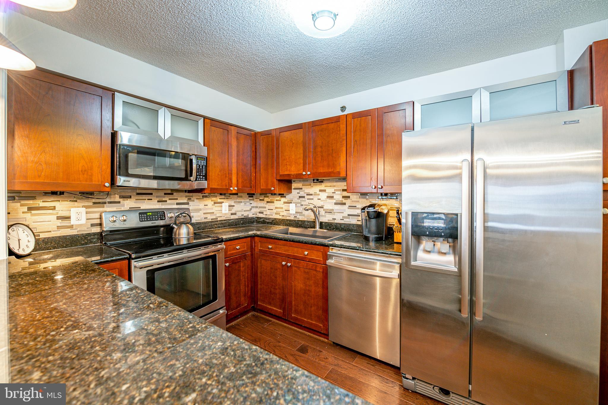 a kitchen with granite countertop wooden cabinets a refrigerator and a stove top oven