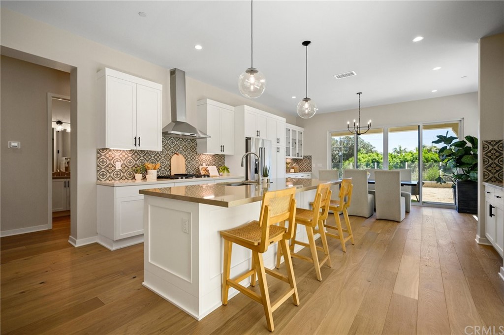 a kitchen with stainless steel appliances kitchen island granite countertop a table chairs and a wooden floor