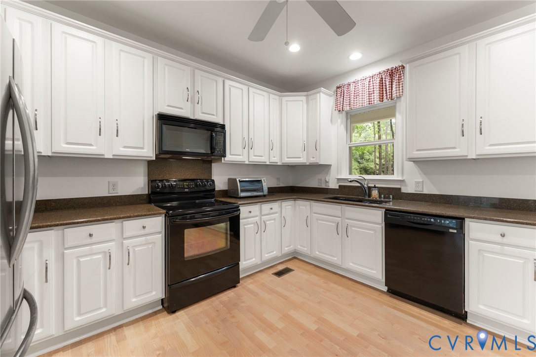 625 Whispering Pines Road Lancaster, VA 22503 - Photo 19 of 71 a kitchen with granite countertop white cabinets and black appliances