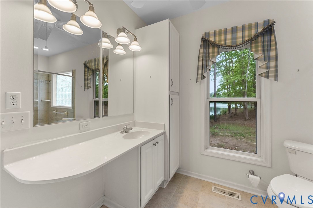 625 Whispering Pines Road Lancaster, VA 22503 - Photo 38 of 71 a bathroom with a sink a toilet and a large mirror