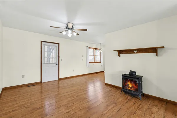 an empty room with wooden floor chandelier fan and windows