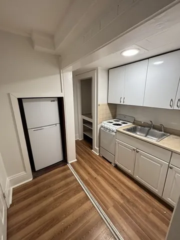 a kitchen with granite countertop a refrigerator a sink and white cabinets