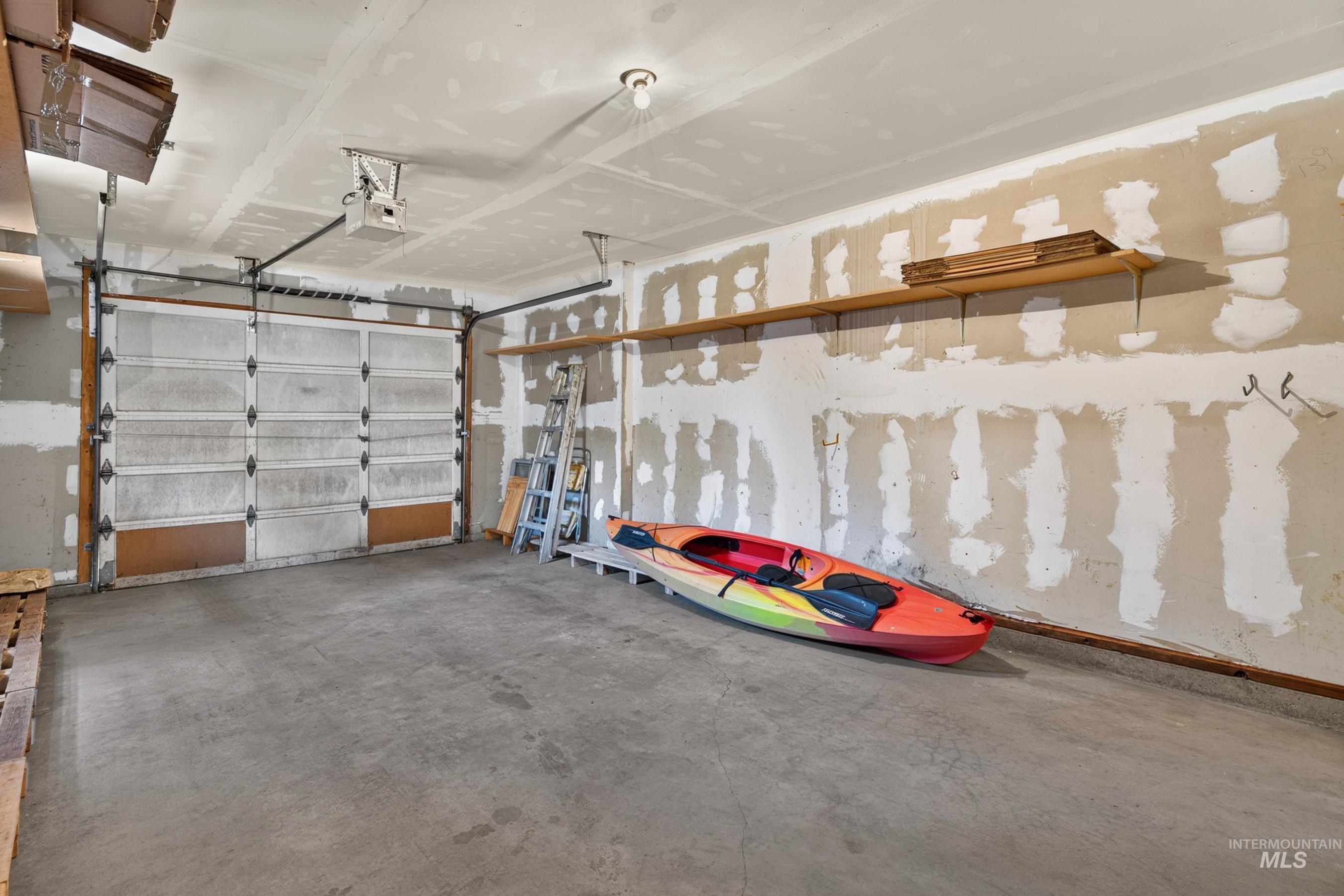 302 Mather Road McCall, ID 83638 - Photo 19 of 24 Garage with a concrete floor, overhead door, exposed ceiling, and wall-mounted shelving