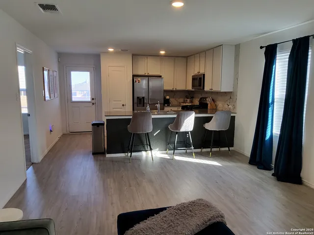 a living room with stainless steel appliances granite countertop furniture wooden floor and a view of kitchen