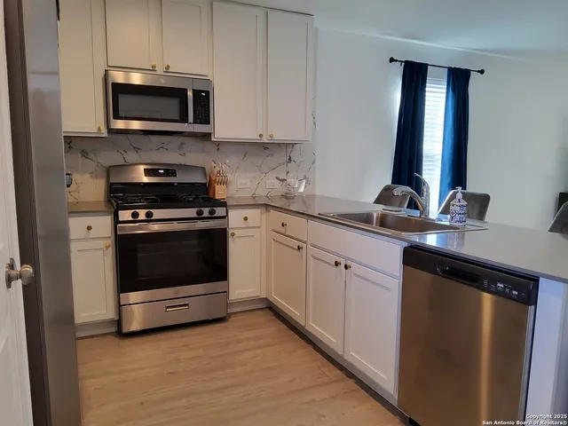 a kitchen with white cabinets and stainless steel appliances