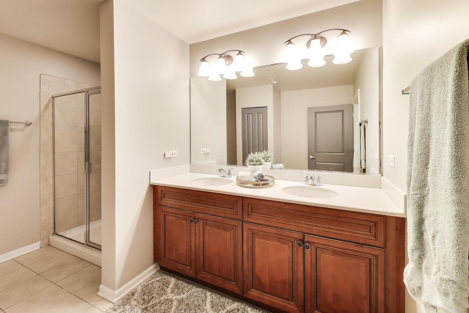 1199 East Port Clinton Road, Unit 311 Vernon Hills, IL 60061 - Photo 14 of 23 a bathroom with a double vanity sink and a mirror