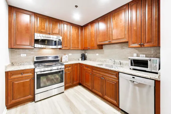 a kitchen with granite countertop wooden cabinets stainless steel appliances and a window