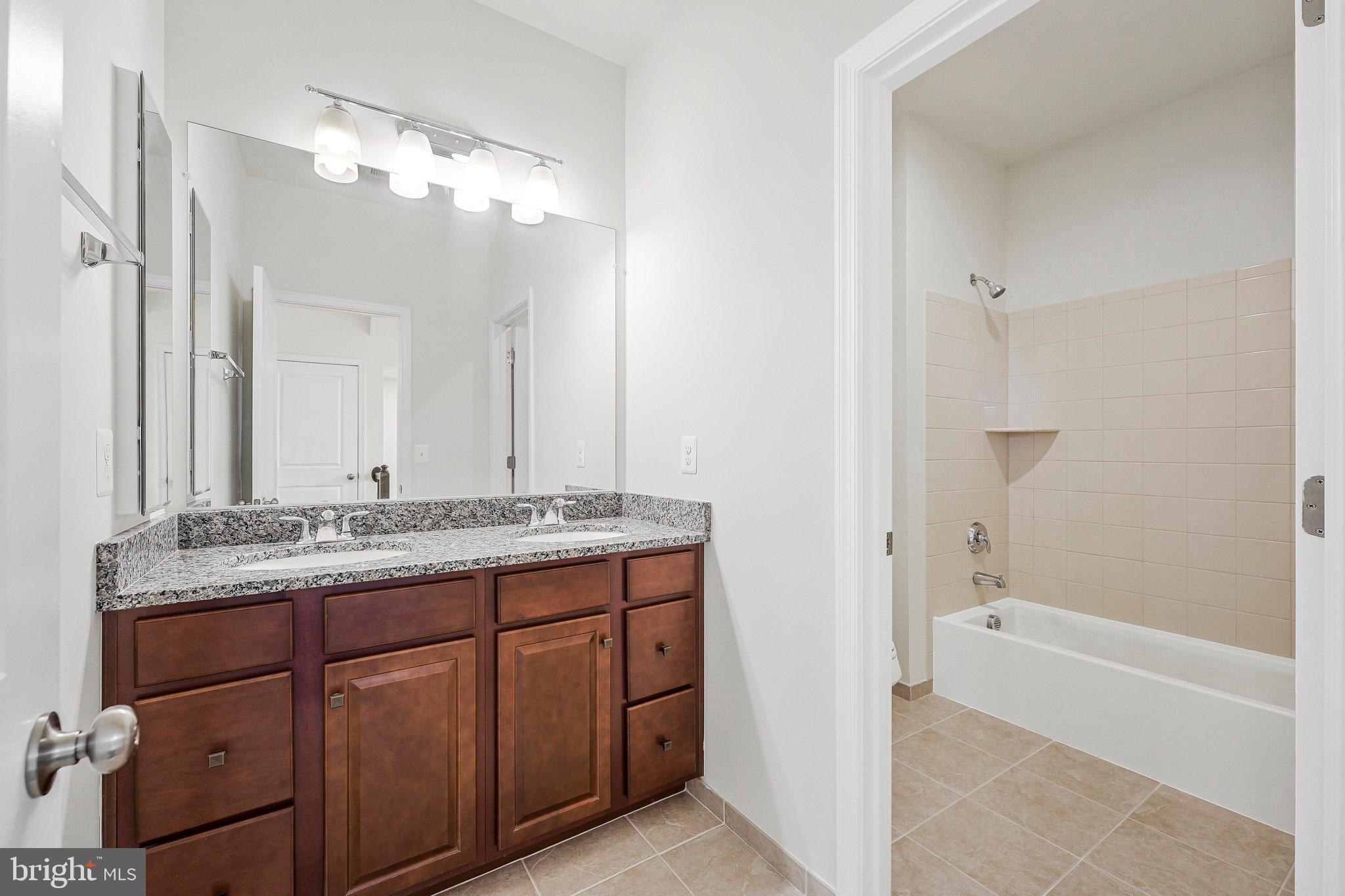 14580 Lakestone Drive Chantilly, VA 20151 - Photo 14 of 21 a bathroom with a granite countertop sink a mirror and a bathtub