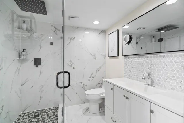 a bathroom with a granite countertop sink a toilet and a shower