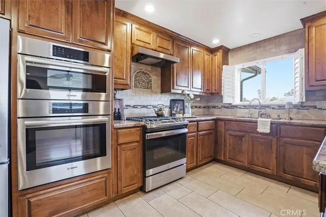 a kitchen with stainless steel appliances granite countertop a stove a sink and a microwave