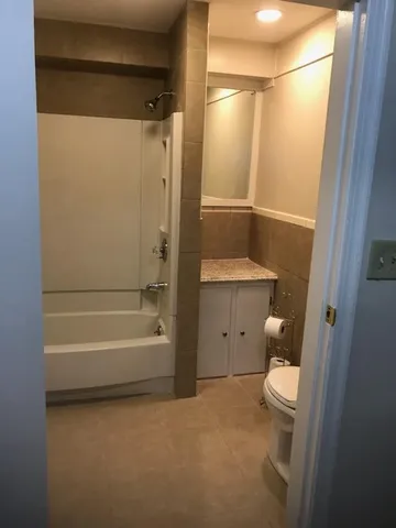 a bathroom with a granite countertop bathtub shower sink vanity and toilet