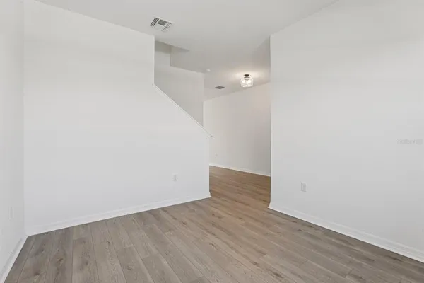 a view of an empty room with wooden floor and a ceiling fan