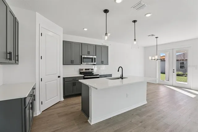 a kitchen with stainless steel appliances granite countertop a sink a stove and a wooden floors