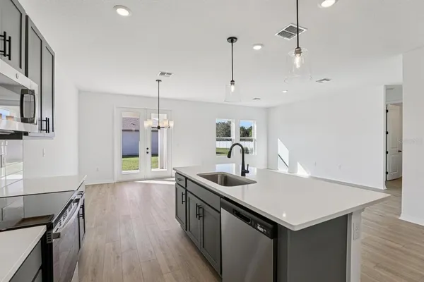 a kitchen that has a lot of cabinets a sink and wooden floor
