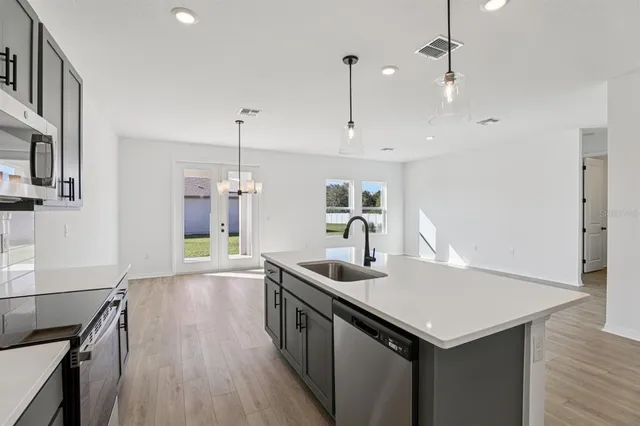 a kitchen that has a lot of cabinets a sink and wooden floor