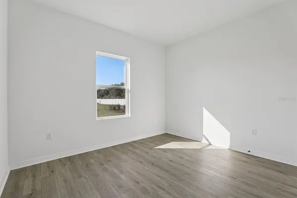 an empty room with wooden floor and window